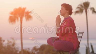 女人在日出时坐着莲花姿势。 健康的生活方式。 早上冥想。 瑜伽冥想的概念。 年轻女子
